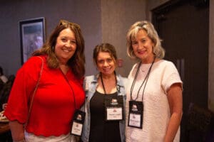 Three women smiling with name tags.