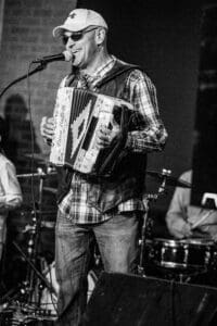 Musician playing accordion and singing on stage.