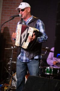 Man playing accordion and singing on stage.