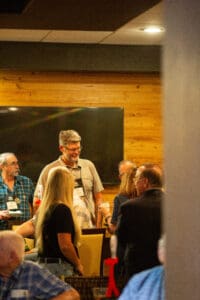 Attendees socializing in wood-paneled event space