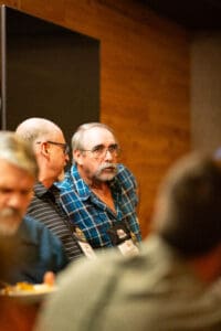 Man in plaid shirt at social gathering.