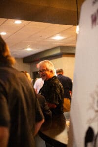 Man smiling at a social gathering indoors.