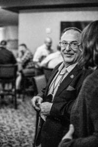 Smiling man at social gathering, black-and-white.