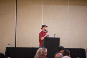 Man speaking at a podium in conference.