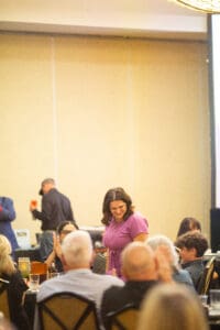 Woman standing in crowded event space smiling.