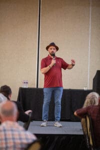 Man speaking on stage with microphone.
