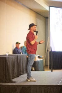 Man in hat speaking on conference stage