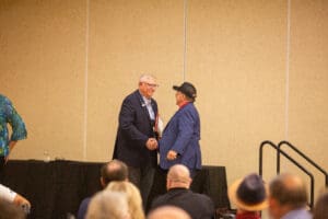 Two men shaking hands on conference stage