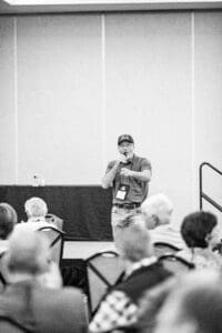 Man speaking at a conference in grayscale.