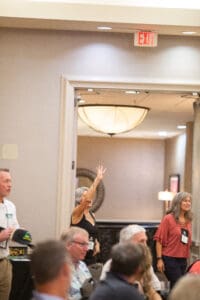 Person raising hand in a conference room.