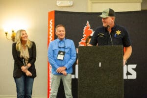 People speaking at an indoor event podium.