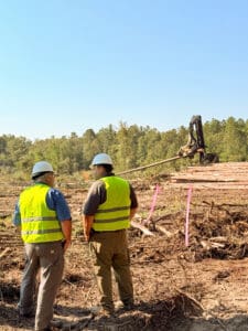 Workers in forest with construction equipment.
