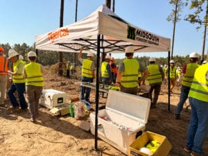 Workers in safety vests under canopy tent.