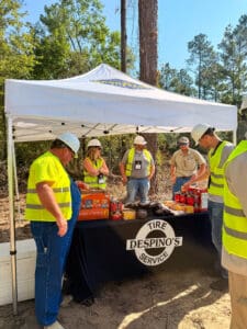 Workers under canopy with safety gear.