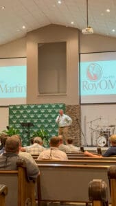 Man speaking at indoor conference event.