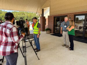 People being interviewed outside a building.