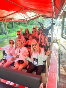 Group enjoying airboat ride under red canopy.
