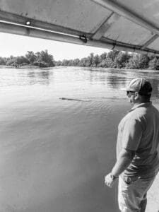 Man observing river from boat, sunny day.