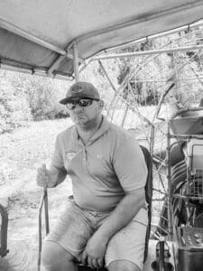 Man steering a boat in sunglasses.
