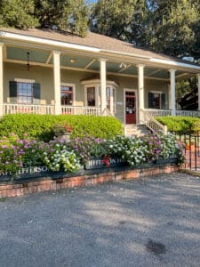 Historic house with porch and blooming flowers.
