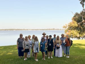 Group standing by a lakeside under trees.