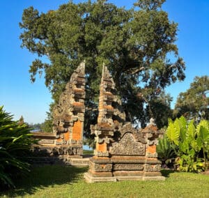 Ornate stone gate with lush greenery background.