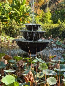 Tiered fountain in lush garden setting.