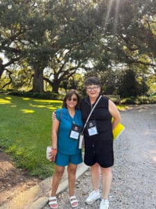 Two people posing outdoors on a sunny day.